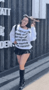a woman wearing a white sweatshirt and a black skirt is walking down the street .