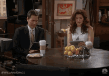 a man and a woman are sitting at a table with nbc written on the table