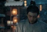 a man in a kimono is standing in front of a bunch of lanterns in the snow .