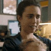 a woman holding a baby in her arms and smiling