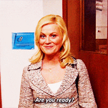 a woman in a suit says " are you ready " in front of a door
