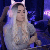 a woman wearing pink headphones with cat ears is sitting in front of a laptop computer .