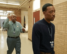 two men are walking down a hallway and one of them has a name tag that says ' a.j. ' on it
