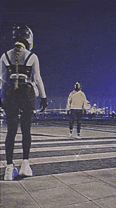 a man and a woman are walking down a street at night ..
