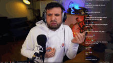 a man wearing headphones and a white hoodie stands in front of a microphone in front of a screen that says les possess
