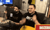 two men sitting on a couch with a sign that says doizero on it