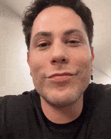 a close up of a man 's face with a black shirt
