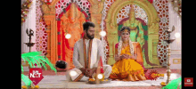 a man and a woman are sitting on the floor in front of a statue .