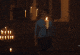 a man in a blue shirt is standing in front of a candle
