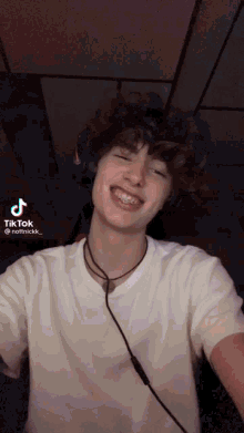 a young man wearing headphones and a white shirt has a tiktok sticker on his face