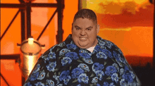 a man wearing a blue and black floral shirt is making a funny face