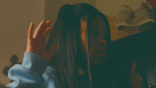 a woman in a blue shirt is holding her hand up