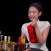 a woman is sitting at a table with a bunch of bottles of hot sauce on it .