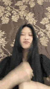 a woman with long black hair is laying on a floral blanket