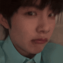 a close up of a young man 's face with a blue shirt on making a funny face .