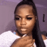 a woman with long black hair is holding her hair in a ponytail and making a funny face .