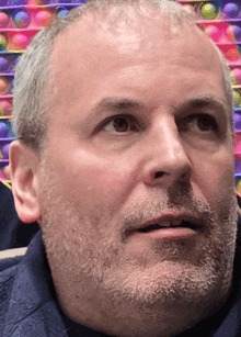 a man with a beard and a blue shirt looks at something