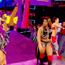a group of women are standing on a purple stage .