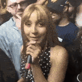a woman in a black and white polka dot dress is holding a microphone
