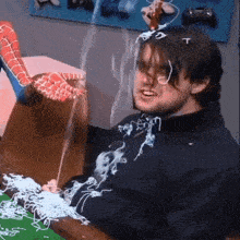 a man is sitting at a table with a spider man toy on his head and glasses .