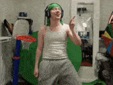 a man wearing headphones and a green headband stands in front of a little tikes basketball hoop