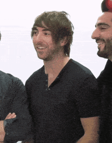a man in a black shirt is smiling while standing next to another man