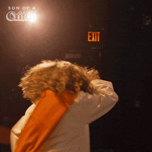 a person standing in front of an exit sign that says son of a critch