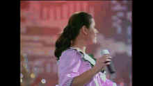 a woman in a purple dress is singing into a microphone .