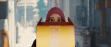 a woman in a pink head scarf is holding a box that says ' a ' on it