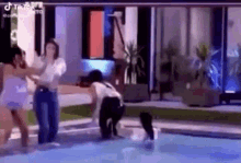 a group of people are standing in a pool .