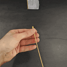 a hand is holding a small stick in front of a box