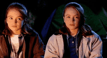 two young girls are sitting next to each other in the dark .