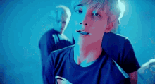 a young man in a blue shirt is standing in front of a blue wall .