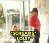 a woman in a red shirt screams i quit in front of a window