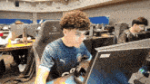 a man with curly hair is sitting in front of a computer wearing a blackrite chair