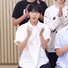 a young man in a white shirt is sitting in front of a group of people clapping their hands .