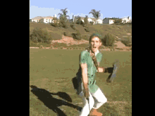 a man in a green costume is standing in a grassy field holding a sword .