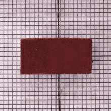 a piece of red brick is sitting on a grid