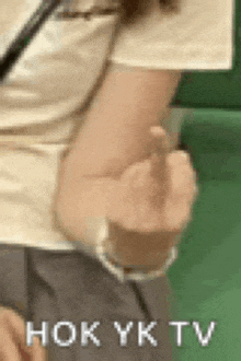 a woman is giving the middle finger while standing in front of a green wall .