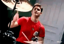 a man in a red shirt is playing drums