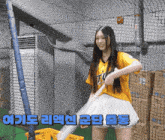 a girl in a yellow shirt and white skirt is holding a baseball bat in front of a cage with chinese writing on it