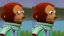 a stuffed monkey with a backpack is standing next to a body of water and making a funny face .