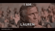 a man is sitting in front of a crowd with a crowd behind him and a caption that says `` i am lauren '' .