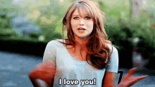 a woman is saying `` i love you '' while holding a red object in her hand .