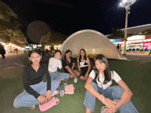a group of girls are sitting on the grass in front of a large dome