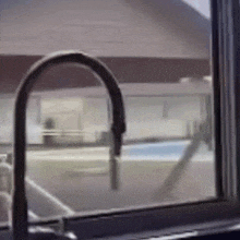 a kitchen sink with a view of a swimming pool behind it