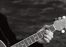 a black and white photo of a man playing a guitar