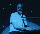 a man singing into a microphone while wearing sunglasses