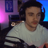 a man wearing headphones is sitting in front of a microphone in a room .