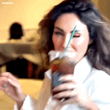 a woman drinking from a plastic cup with a green straw and the word anabiooo on the bottom right